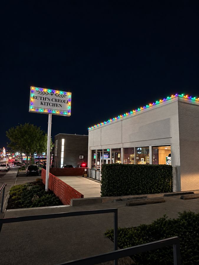 Restaurant at night with colored lights installed along the roofline and around the street sign