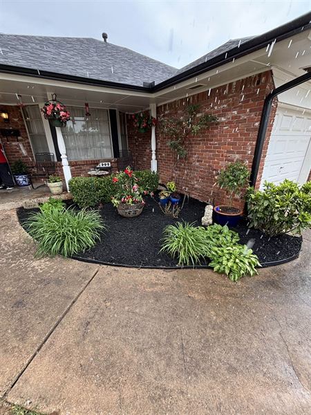 Porch flower bed with black mulch, liriope, and hostas