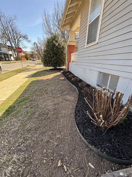 Freshly mulched bed with clean edge along the side of a white house