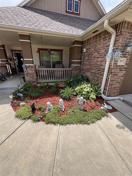 Garden bed with fresh orange mulch, hostas, and flowering plants