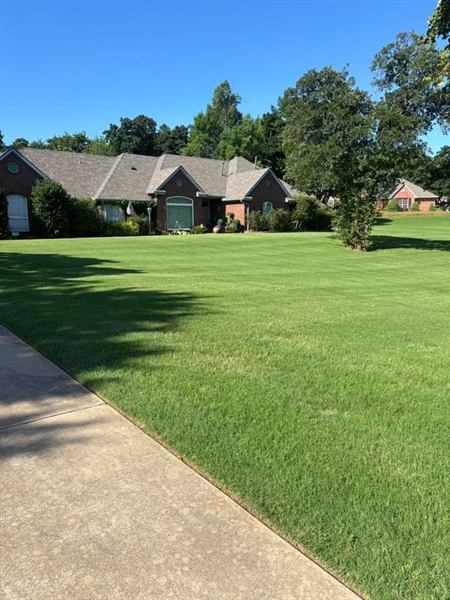 Wide green front lawn in front of a brick home