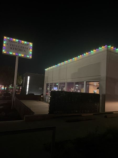 Restaurant at night with colored lights along the roofline and around the street sign