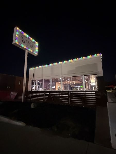 Street sign framed in colored lights with the lit restaurant roofline behind it